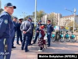 Алматыда полицейлер мен әкімдік өкілдері митинг белгіленген жерге келген зейнеткермен сөйлесіп тұр. 25 қазан 2023 жыл.