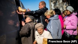 Locals line up to receive food and everyday necessities given by Ukrainian volunteers in Izyum, where residents have been living without gas, electricity, or running water supply since the beginning of September. 