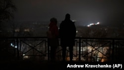 People stand amid a blackout after a Russian missile attack in Kyiv on November 23. 