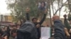 Protester Mehrshad Shahidinejad (center) holds up a picture of his father, who is one of the victims of the crackdown on protests in Iran, on November 3.