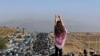 An unveiled woman stands on top of a vehicle as thousands make their way towards the cemetery in Saghez, Mahsa Amini's hometown in Kurdistan Province, to mark 40 days since her death in late October.