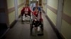 Followed by their mother Natasha, Yarik Stepanenko, 11, pushes his twin sister Yana's wheelchair along a corridor of a public hospital in Lviv on May 12. They were injured on April 8 when a Russian missile struck the train station in the eastern city of Kramatorsk.