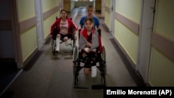 Followed by their mother Natasha, Yarik Stepanenko, 11, pushes his twin sister Yana's wheelchair along a corridor of a public hospital in Lviv on May 12. They were injured on April 8 when a Russian missile struck the train station in the eastern city of Kramatorsk.