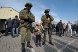 A child poses for a picture with Russian servicemen during a demonstration of military equipment and hardware on the Defender of the Fatherland Day in Sevastopol, Crimea, on February 23.