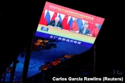 A giant screen broadcasts news footage of a virtual meeting between Chinese President Xi Jinping (right) and Russian President Vladimir Putin at a shopping mall in Beijing in December 2021.