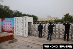 Foreign journalists take photos and record videos outside a location in China's Xinjiang region that was identified in early 2020 as a "reeducation" facility.