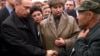 Russian President Vladimir Putin (left) shakes hands with an unidentified relative of a crew member of the Kursk, as Irina Lyachin (center), the wife of the commander of the submarine, looks on, in the town of Vidyayevo on August 22, 2000.