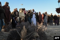 Afghan men gather around the grave of Khalil Ur-Rahman Haqqani, the Taliban refugees and repatriation minister. The Islamic State group claimed his assassination in December.