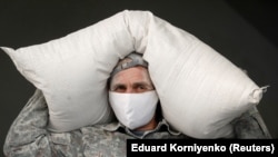 An employee wearing a protective mask, used as a measure against the coronavirus, carries a bag with flour at a bakery in the city of Nevinnomyssk in the Stavropol region on March 27.