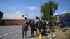 Security personnel prepare for deployment beside shipping containers placed by authorities blocking the Islamabad-Rawalpindi highway to stop protesters from entering the capital for an anti-France rally.