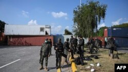 Security personnel prepare for deployment beside shipping containers placed by authorities blocking the Islamabad-Rawalpindi highway to stop protesters from entering the capital for an anti-France rally.