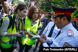 Полиция өкілі шеруден хабар әзірлеуге келген журналистердың құжаттарын тексеріп тұр. Алматы, 9 мамыр 2019 жыл.