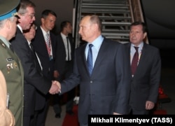 Russian President Vladimir Putin greets officials upon his arrival at the airport in Hamburg on July 7.