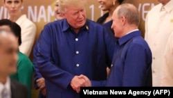 U.S. President Donald Trump (left) shakes hands with Russia's President Vladimir Putin as they pose for a group photo ahead of the APEC summit leaders' dinner in Danang, Vietnam, on November 10.