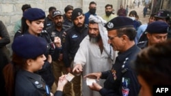 Security personnel check documents of Afghan refugees in Karachi in 2023.