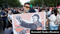 A demonstrator holds a placard depicting Hungarian Prime Minister Viktor Orban as Mao Tse-tung during a protest against the planned Chinese Fudan University campus in Budapest in June 2021.