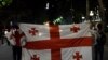 Protesters waive the Georgian flag near the parliament building in Tbilisi early on June 26.