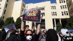 An Iranian woman, hiding her face so as not to be identified, raises a placard during a protest to show solidarity with the acid-attack victims, in front of the judiciary building in Isfahan on October 22.