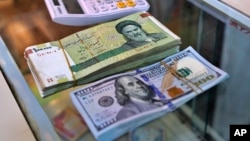 A pile of Iranian rials sits next to a stack of U.S. dollars. Iran's national currency hit a record low on February 11.